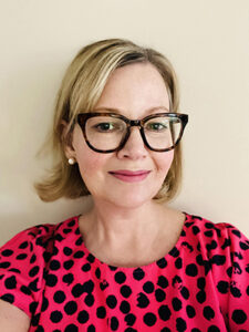 A woman wearing glasses and a pink polka dot shirt.